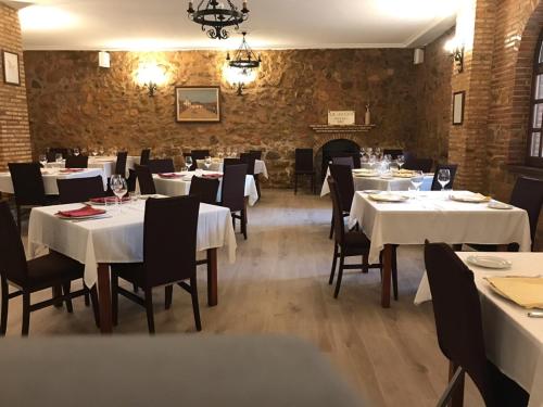 a restaurant with white tables and chairs and a fireplace at Hotel Rural Abadía de Yuste in Cuacos de Yuste