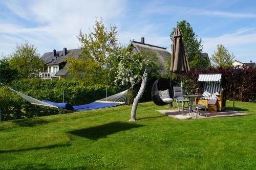 a yard with hammocks and a table and an umbrella at Reethaus Casa Baltica in Börgerende-Rethwisch