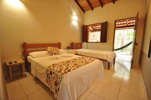 a hotel room with two beds and a window at TEMPLÁRIOS ECOVILLA Pousada in Pirenópolis