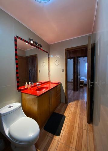 a bathroom with a red sink and a toilet at Cabaña Nueva Norte in Lanco