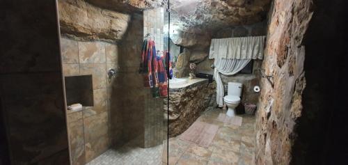 y baño de piedra con ducha y aseo. en Kings View Cave, en Clanville