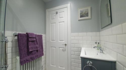 a bathroom with a sink and a shower with purple towels at Willows Apartment in Pitlochry