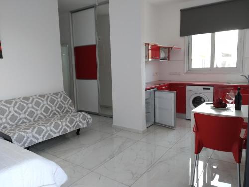 a bedroom with a couch and a kitchen with red cabinets at Dream- Downtown-Studios in Paphos City