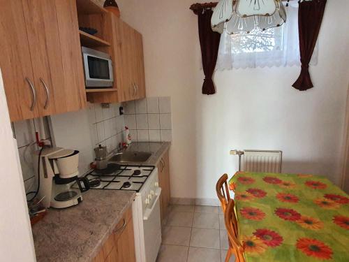 a small kitchen with a table and a stove top oven at Szekrény Apartman in Lenti