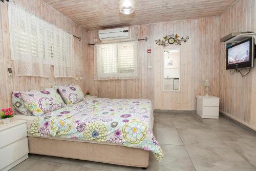 a bedroom with a bed and a flat screen tv at Leyad Hashmura Lodging in Yesod Hamaala