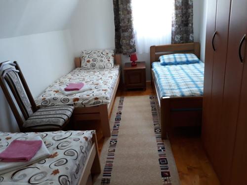 um pequeno quarto com 2 camas e uma cadeira em House in forest em Žabljak