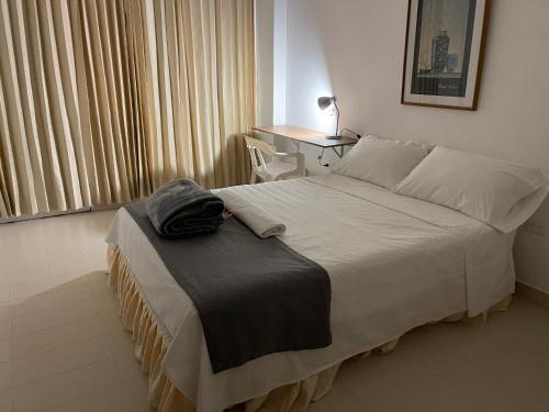 a bedroom with a large bed with a desk and a table at Hotel Luna Roja del Llano in Yopal