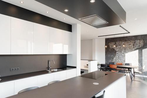 a kitchen with white cabinets and a table with chairs at Boonuz guesthouse, luxe duplex vakantiehuis in centrum Ieper met privé lounge terras en IR sauna in Ieper