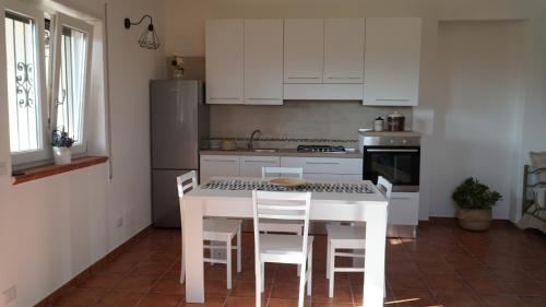 a kitchen with white cabinets and a white table and chairs at Home sweet Home in Metaponto