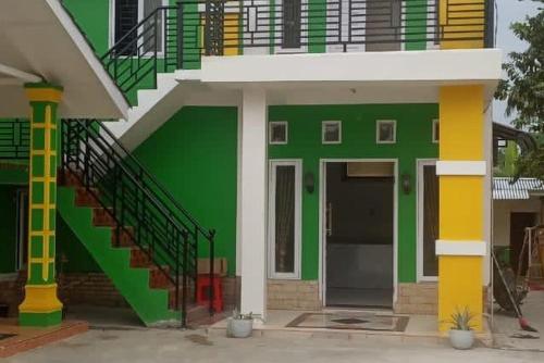 um edifício verde com uma escada e uma porta em Green House Syariah Mitra RedDoorz em Rantauprapat