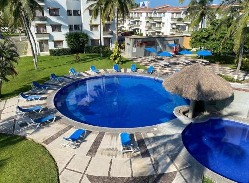 a large swimming pool with chairs and an umbrella at Cocotero Manzanillo in Manzanillo