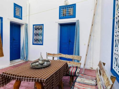 a table and chairs in a room with blue doors at Maison d'hôte Chama in Kairouan