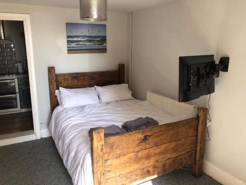 um quarto com uma cama de madeira e uma televisão em Sea view studio em Felixstowe
