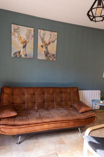 a brown leather couch against a blue wall with three pictures at Apartamento Turístico Snow Boutique in Camarena de la Sierra