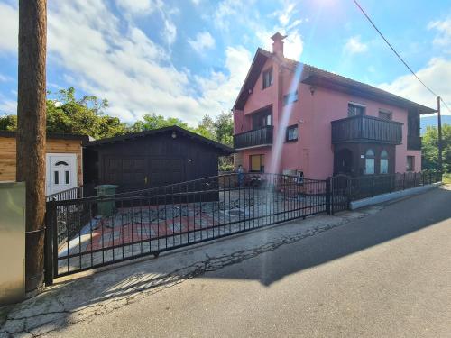 a pink house with a fence in front of it at IN Pavlović in Banja Koviljača