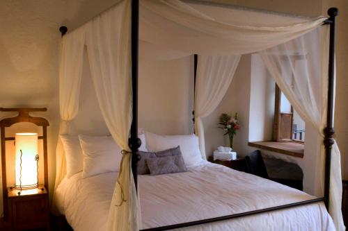 a bedroom with a canopy bed with white sheets and pillows at La Casa del Naranjo Hotel Boutique in Querétaro