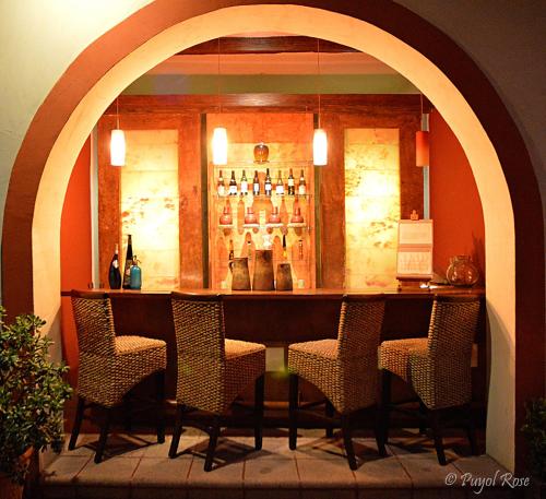 a bar with chairs and a counter with bottles at La Casa del Naranjo Hotel Boutique in Querétaro