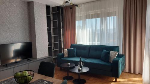 ein Wohnzimmer mit einem blauen Sofa und einem Tisch in der Unterkunft Apartman Green Lux in Banja Luka