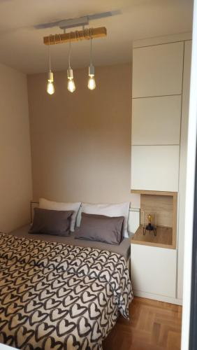 Schlafzimmer mit einem Bett mit einer schwarzen und weißen Bettdecke in der Unterkunft Apartman Green Lux in Banja Luka