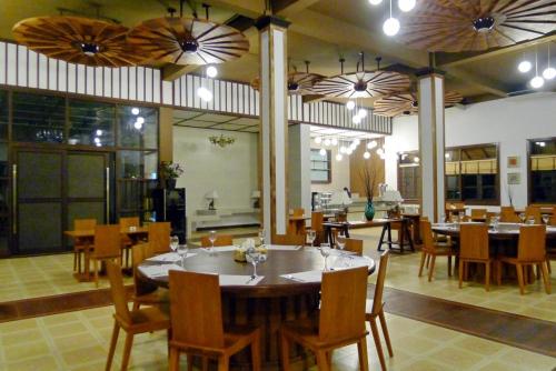 a dining room with tables and chairs and a kitchen at Pearl Laguna Resort in Myeik