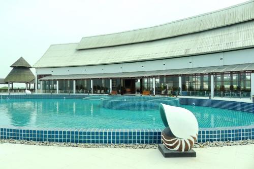 a large swimming pool with a building in the background at Pearl Laguna Resort in Myeik