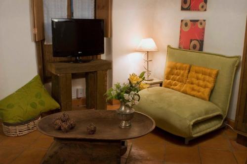 a living room with a couch and a table and a tv at La Casa del Naranjo Hotel Boutique in Querétaro