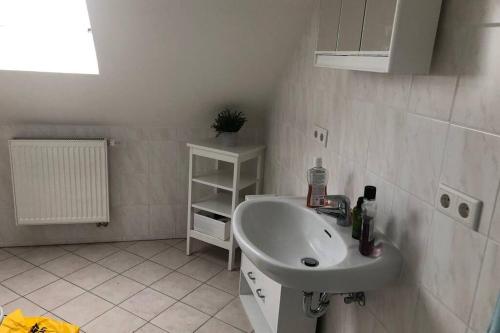 a white bathroom with a sink and a shelf at Kur-Pur eine Ferienwohnung mit Sauna und Garten in Husum