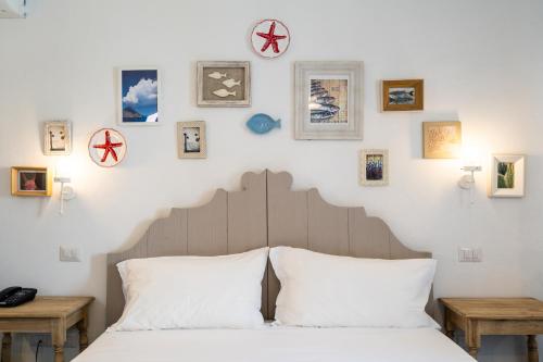 a wall with a bed, a clock, and a painting on it at Hotel La Sciara in Stromboli