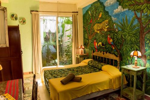 Schlafzimmer mit einem Bett mit Wandgemälde in der Unterkunft Majikal B&B - La Selva in Mérida