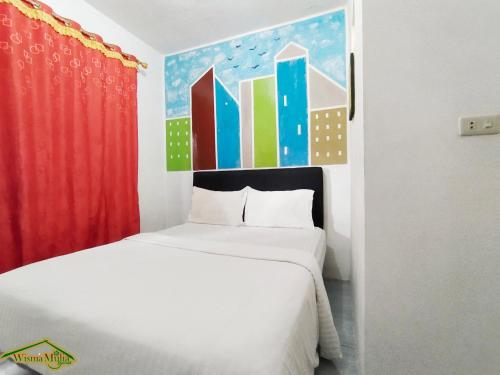 ein Schlafzimmer mit einem Bett und einem Gemälde an der Wand in der Unterkunft Wisma Mulia Syariah Bandar Lampung in Hajimana