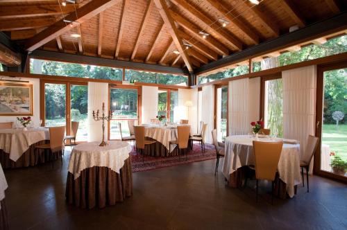 ein Esszimmer mit Tischen, Stühlen und Fenstern in der Unterkunft Eurohotel Palace Maniago in Maniago