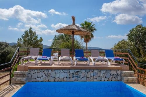 eine Terrasse mit Stühlen und einem Sonnenschirm neben einem Pool in der Unterkunft Son Vorera, situada en una colina, con piscina. in Es Carritxo