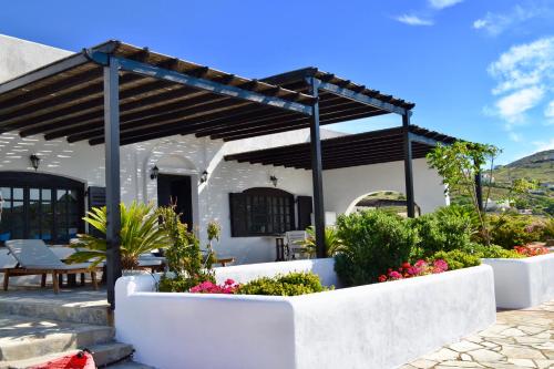a patio with a pergola and flowers at Hersonissos Andros in Gavrion