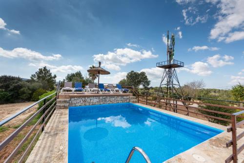 ein Pool auf dem Deck eines Hauses mit einer Windmühle in der Unterkunft Son Vorera, situada en una colina, con piscina. in Es Carritxo