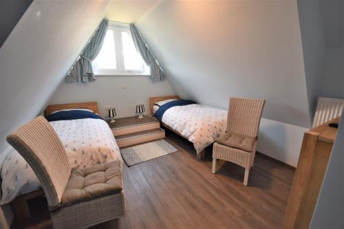a attic room with two beds and a chair at Dat Smucke Huus - 6 Personen strandnah unter Reet in Boltenhagen - 3 SZ - Finnische Sauna - 2 Strandkörbe - Strand 650m in Boltenhagen