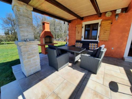a patio with a table and chairs and a fireplace at House in nature in Tinjan