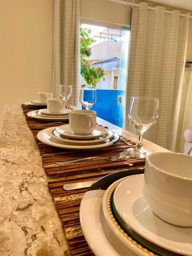 a table with plates and cups and wine glasses at Casinhas da Vila - Itacaré in Itacaré
