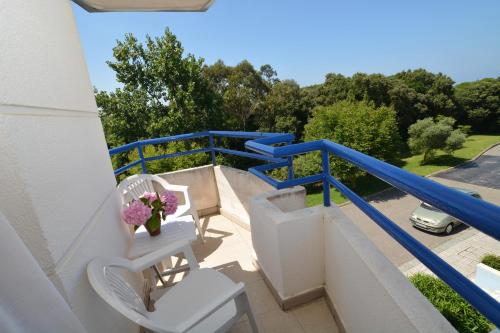 a balcony with two chairs and a vase of flowers at Apartamentos La Arena in Isla