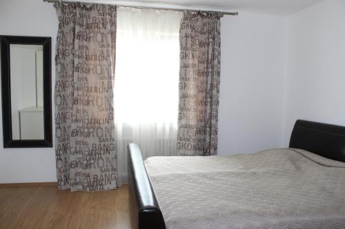 Schlafzimmer mit einem Bett und einem Fenster mit Vorhängen in der Unterkunft Apartment aPriori-Baden-Baden in Baden-Baden