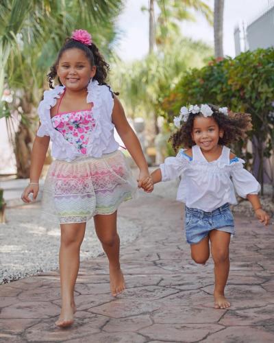 two little girls holding hands while walking down a street at Cadushi Apartments in Oranjestad