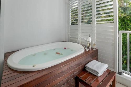 Una bañera colocada encima de una plataforma de madera. en Beach Club Palm Cove Serenity Wing 3 Bed Penthouse, en Palm Cove