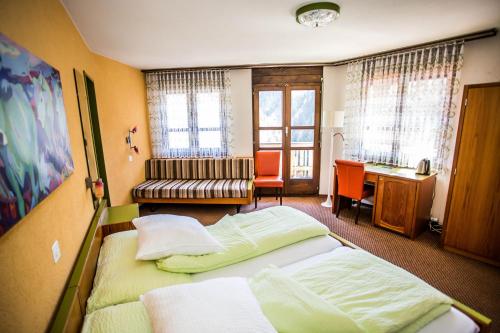 a hotel room with two beds and a desk at Hotel Derby in Fiesch