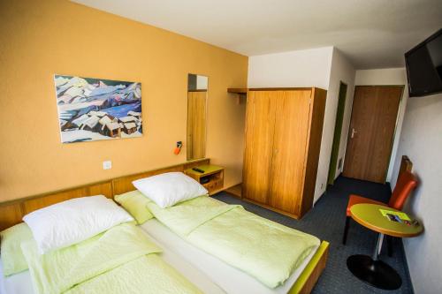 a bedroom with two beds and a desk and a chair at Hotel Derby in Fiesch