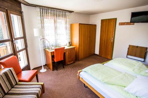 a bedroom with two beds and a desk and a chair at Hotel Derby in Fiesch