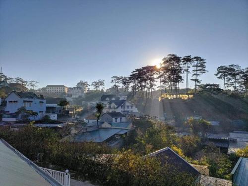 a view of a city with the sun shining through trees at Homestay BỒ CÔNG ANH in Da Lat