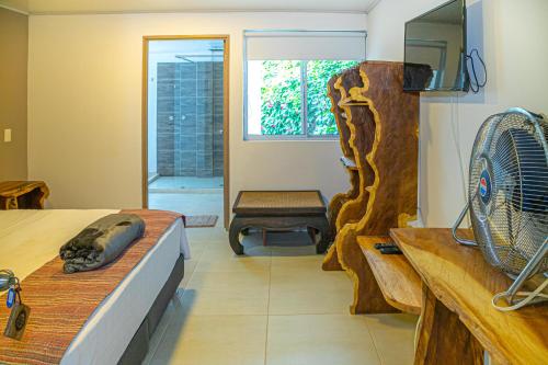a room with a bed with a fan and a bench at Hotel Hacienda Buena Vista in Pueblo Tapao