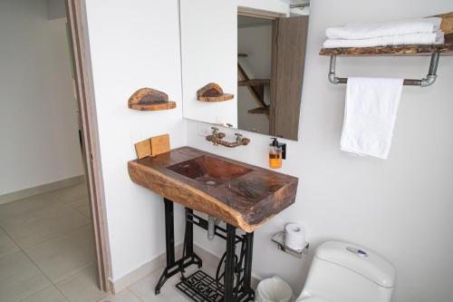 a bathroom with a wooden sink and a toilet at Hotel Hacienda Buena Vista in Pueblo Tapao