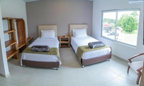 a bedroom with two beds and a window at Hotel Hacienda Buena Vista in Pueblo Tapao