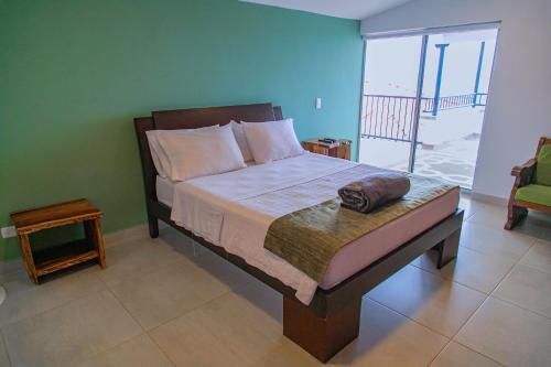 a bedroom with a bed with a view of a balcony at Hotel Hacienda Buena Vista in Pueblo Tapao