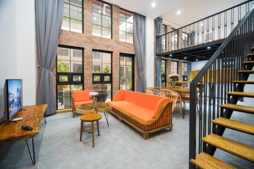 ダナンにあるFlexi Hotel & Apartmentのオレンジ色のソファと階段が備わるアパートメントです。